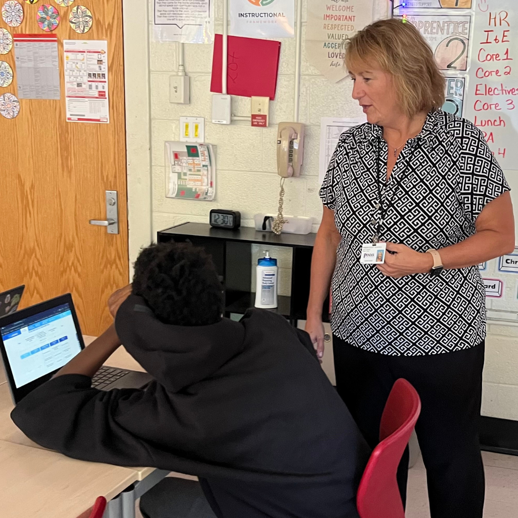 teacher helping student working on computer