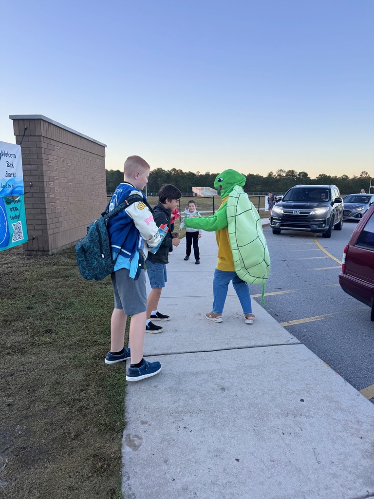 staff member dressed up as a sea turtle welcoming student at the morning car line