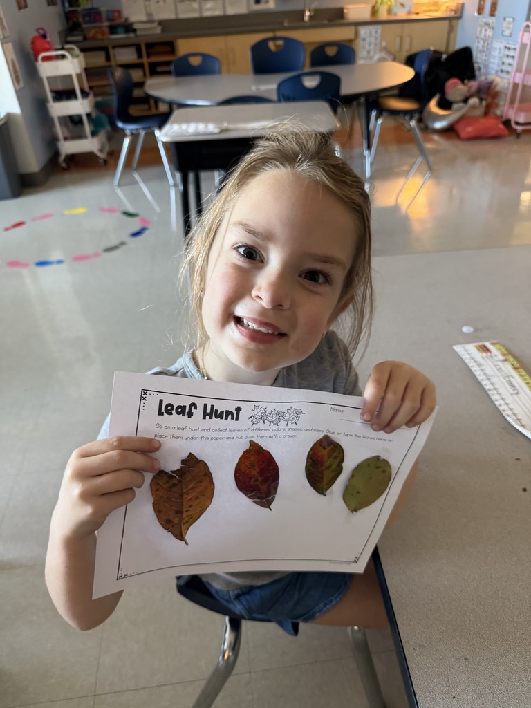 Kindergarten student holding up a leaf project