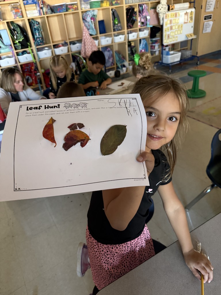 Kindergarten student holding up a leaf project