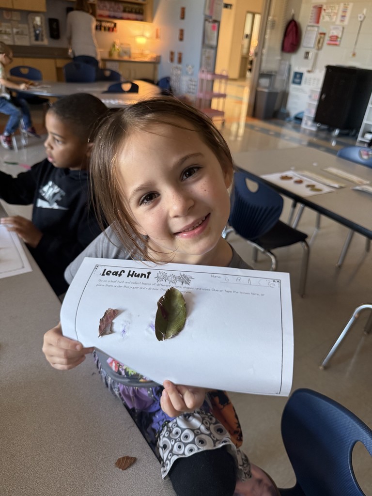Kindergarten student holding up a leaf project