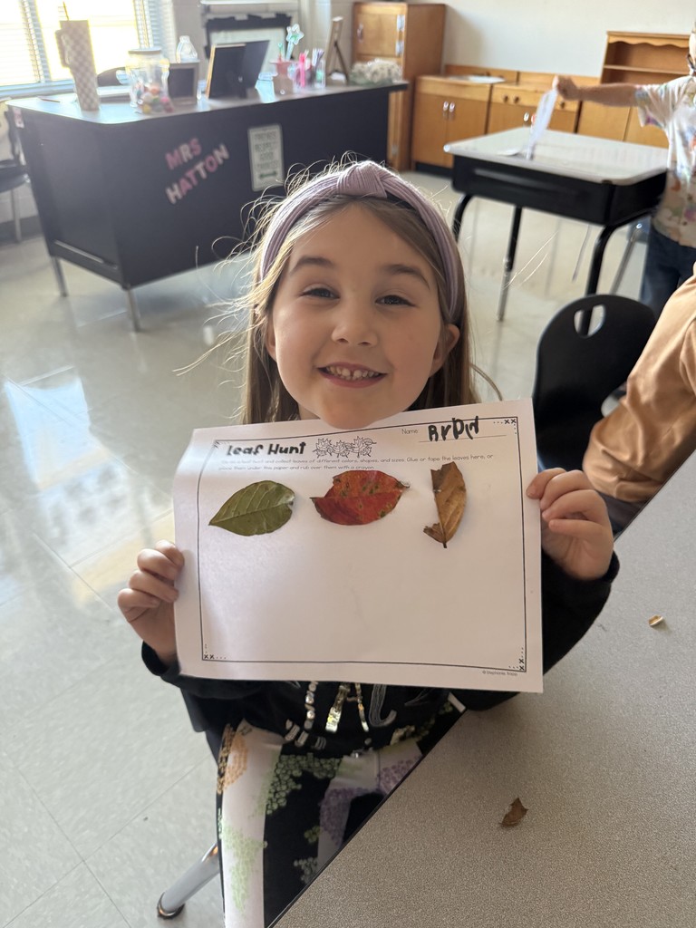 Kindergarten student holding up a leaf project