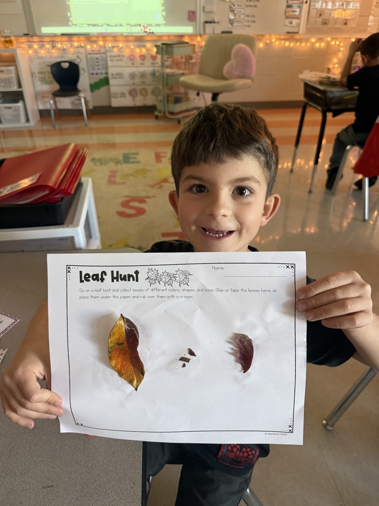 Kindergarten student holding up a leaf project