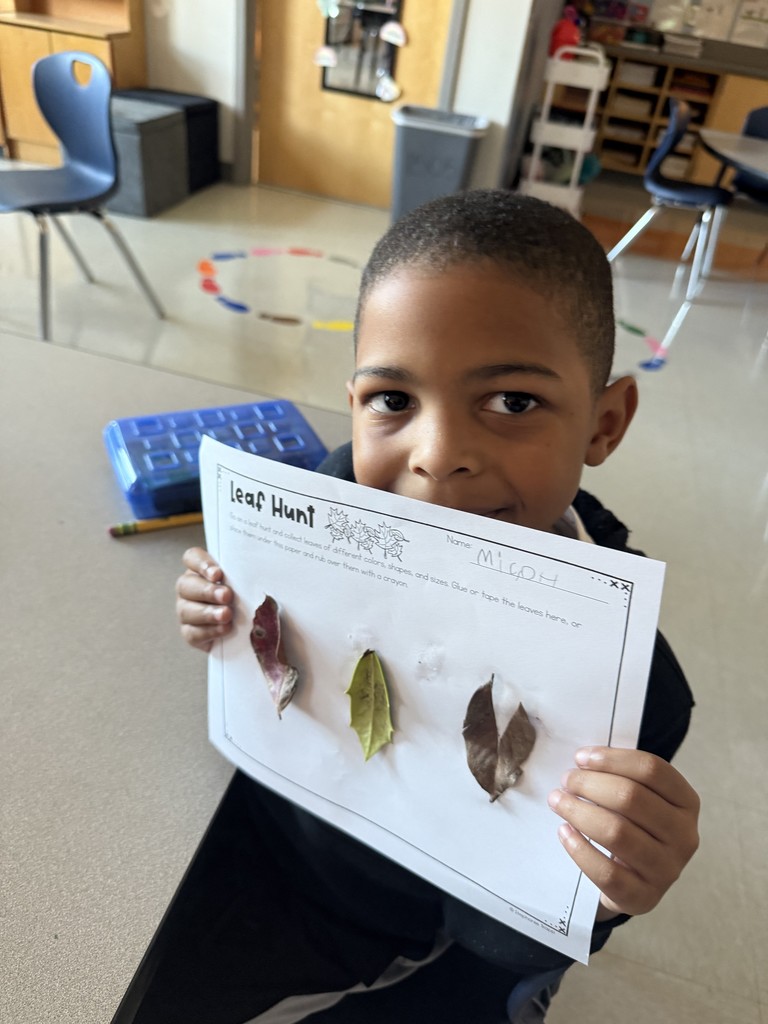 Kindergarten student holding up a leaf project