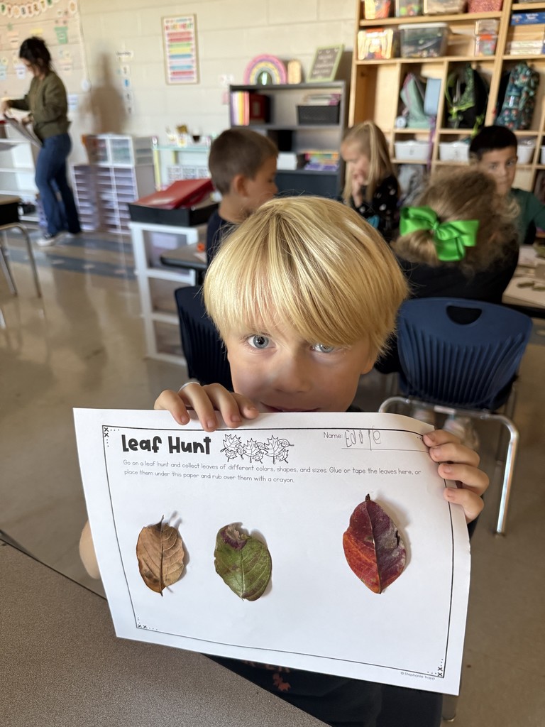 Kindergarten student holding up a leaf project