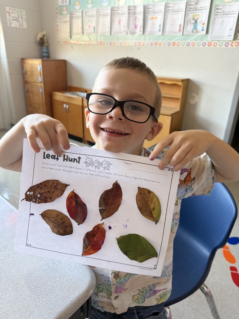 Kindergarten student holding up a leaf project