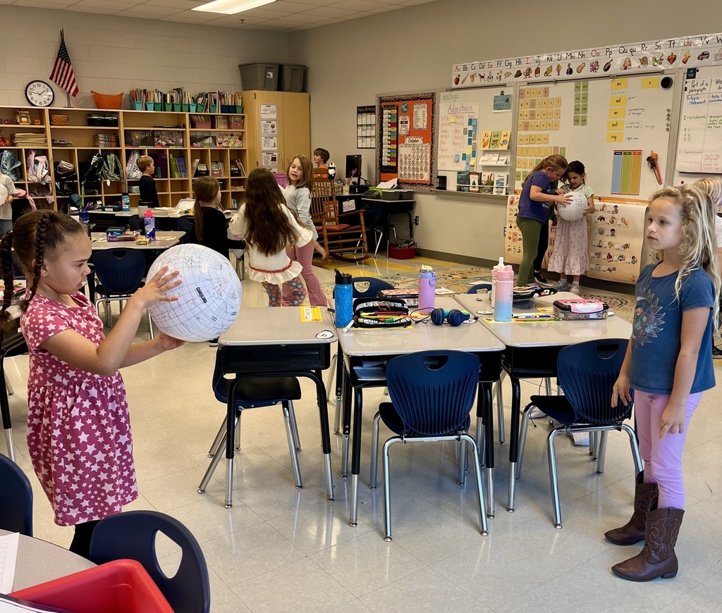 2nd graders holding beach balls with maps on them