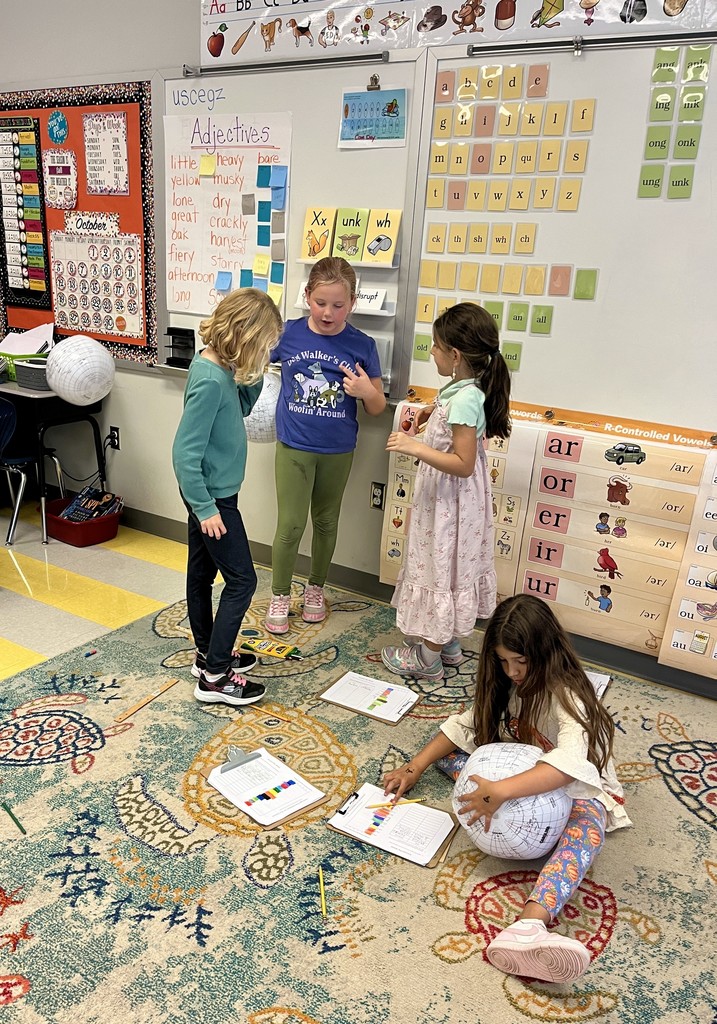 2nd graders holding beach balls with maps on them