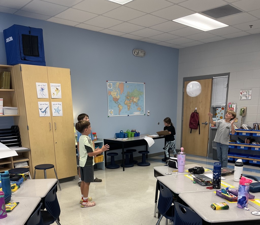 2nd graders holding beach balls with maps on them