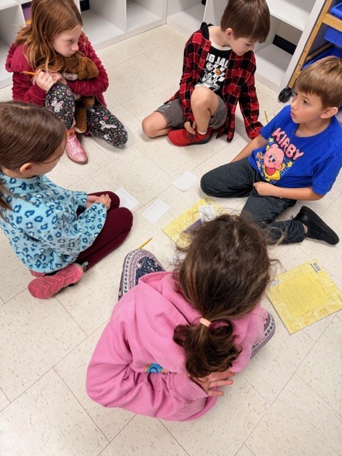 third graders working in small groups on the classroom floor