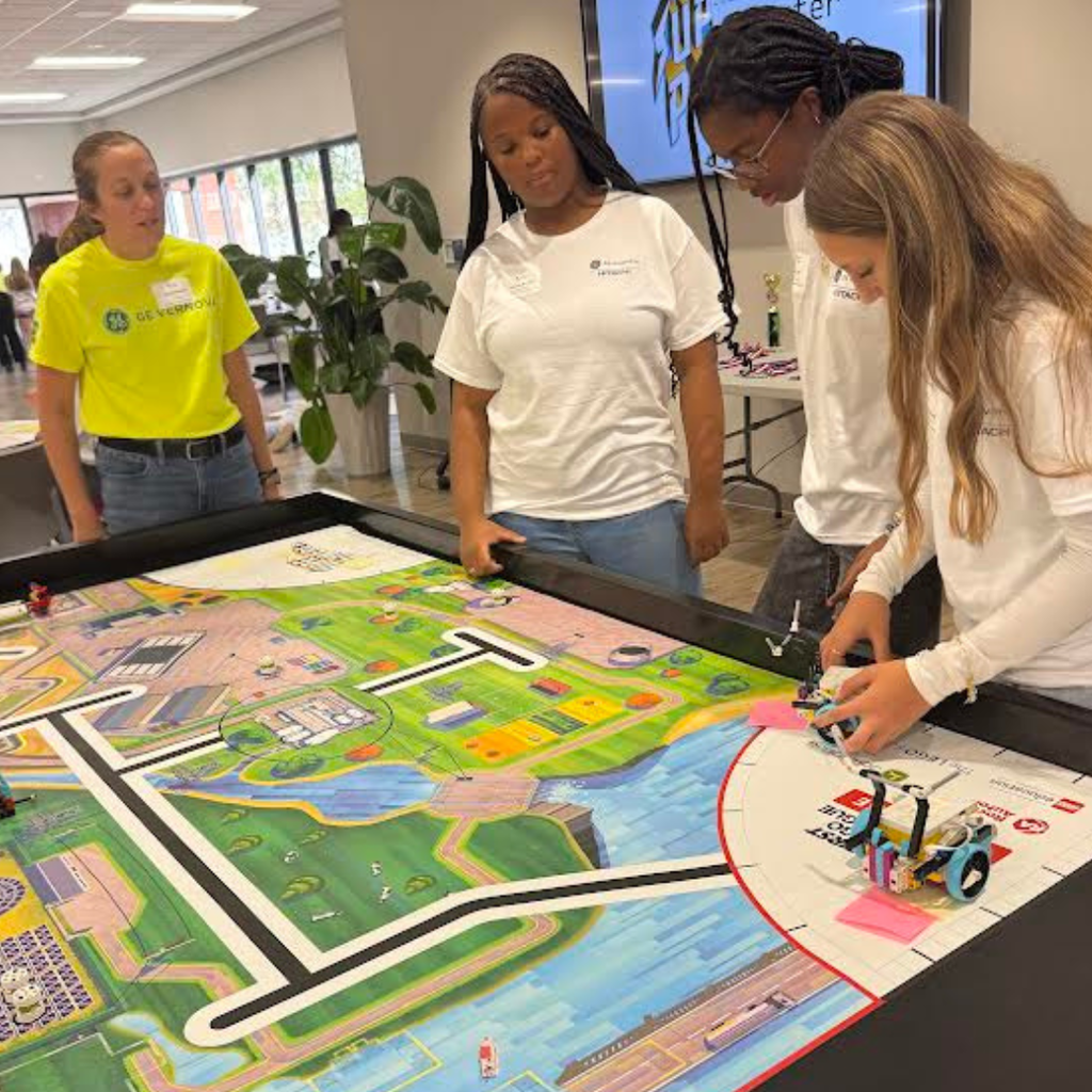 girls in technology group standing at table and working together
