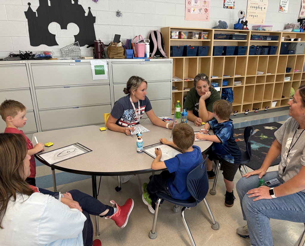 students sitting at a teacher table working on math