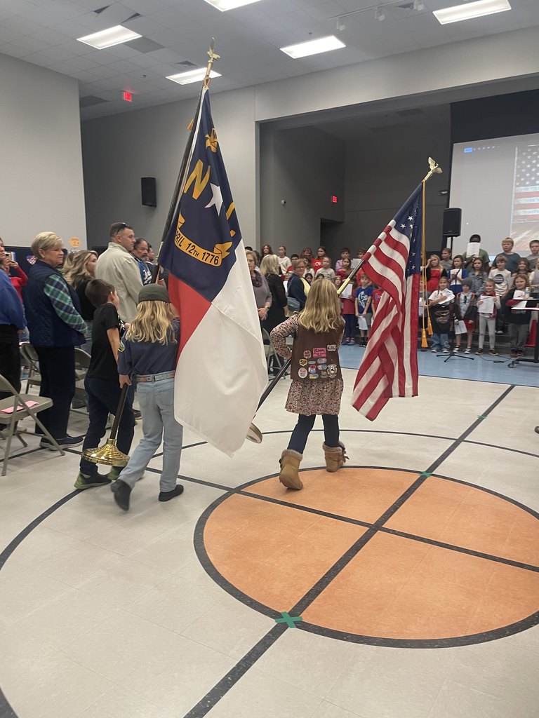 4th grade students walking in the american and state flags at a concert