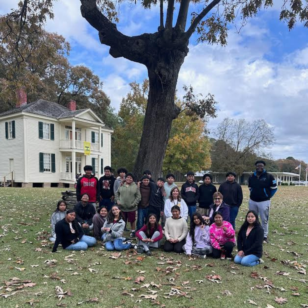 students and teachers posing under tree on field trip