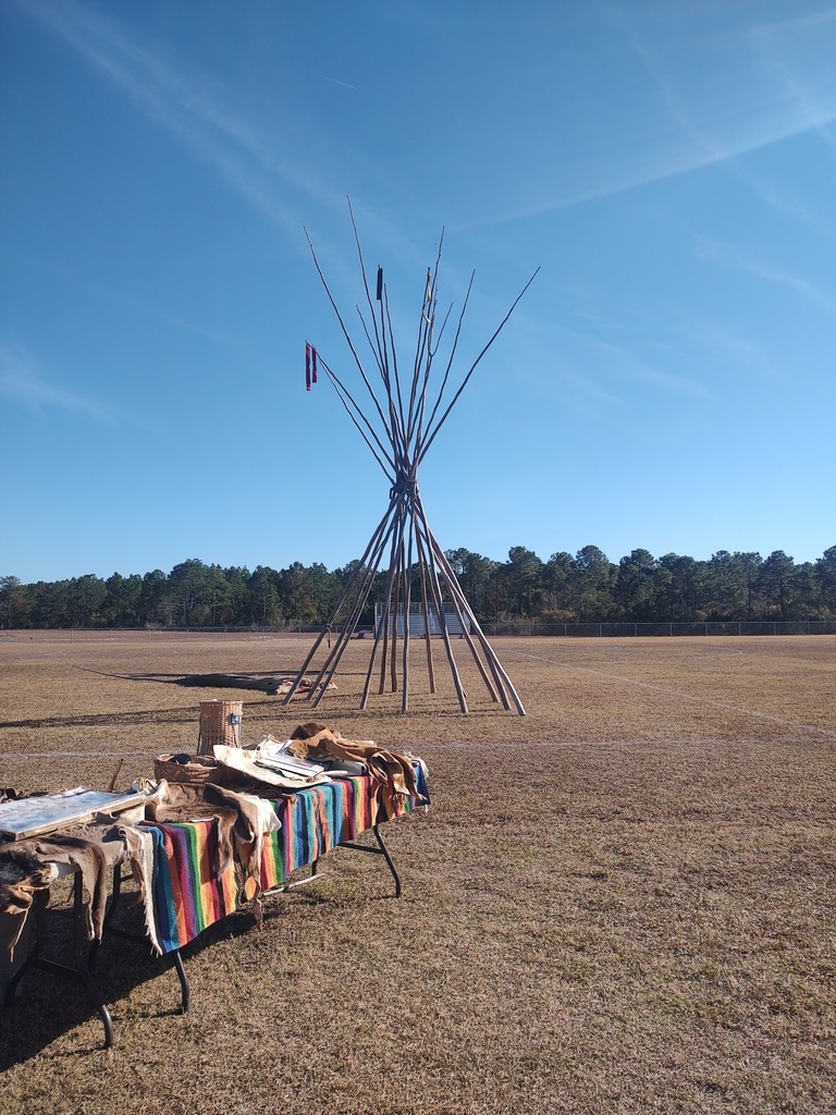 Native American teepee being set up outside 