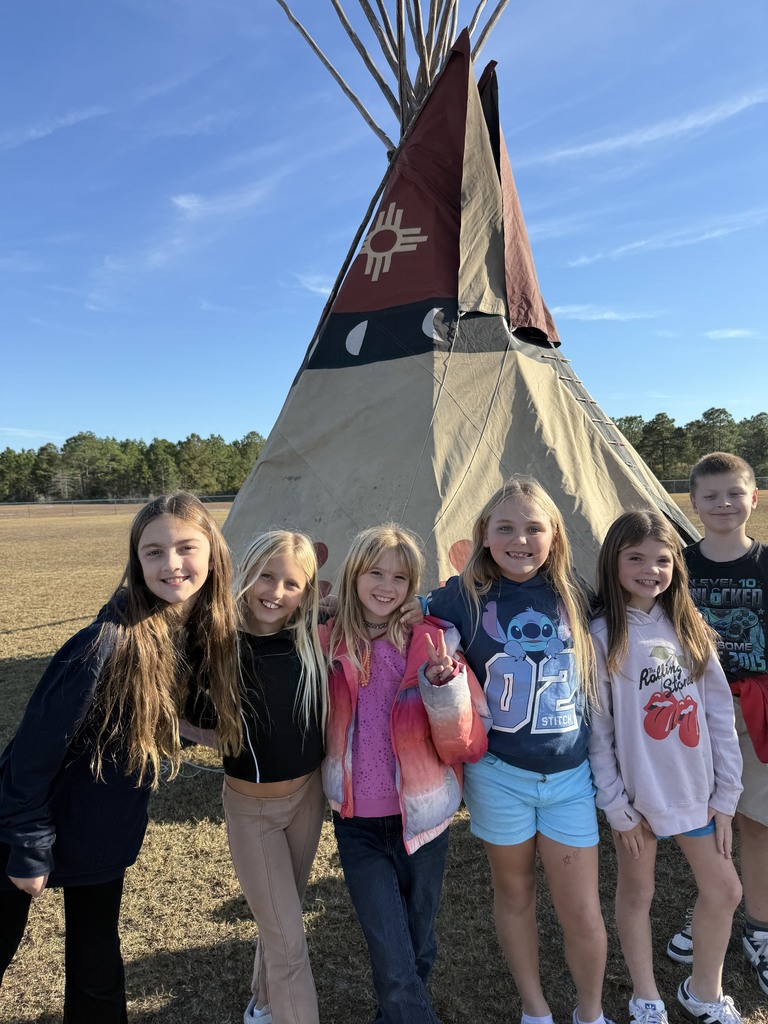 4th grade students standing outside Native American teepee
