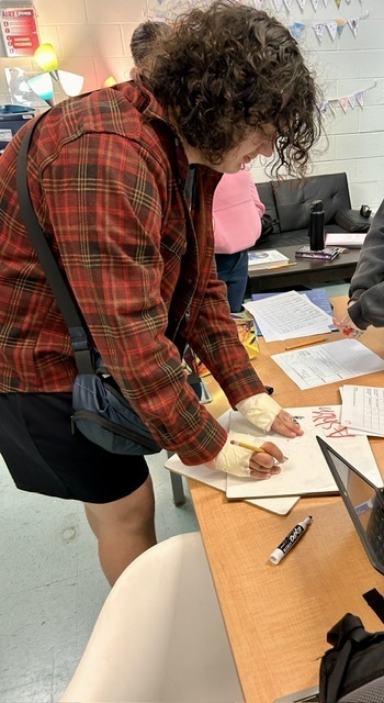 student writes name on board