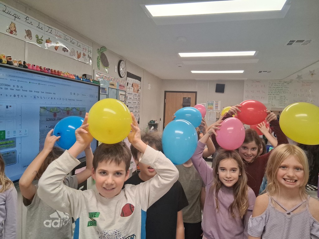 3rd grade students holding balloons on their heads