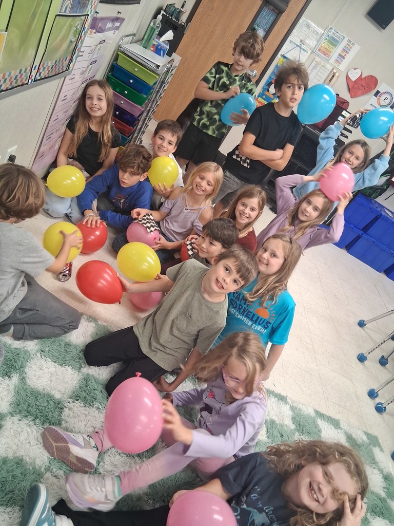 3rd grade students holding balloons on their heads