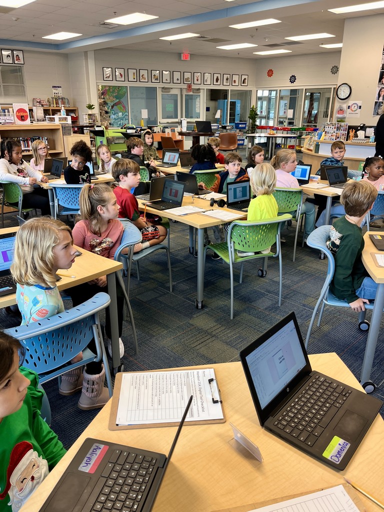 2nd grade students sitting on the carpet with chromebooks working on a lesson