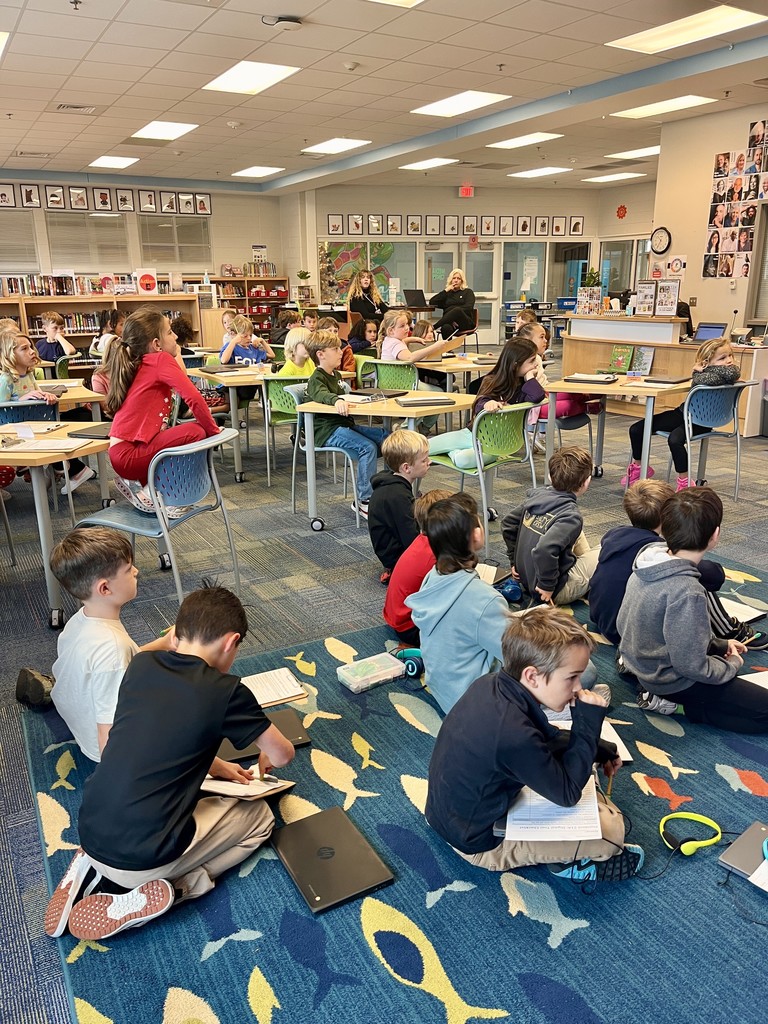 2nd grade students sitting on the carpet with chromebooks working on a lesson