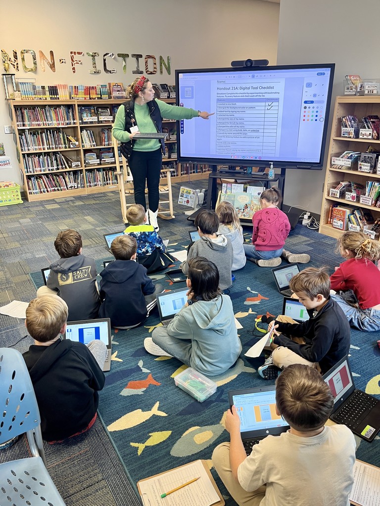 2nd grade students sitting on the carpet with chromebooks working on a lesson