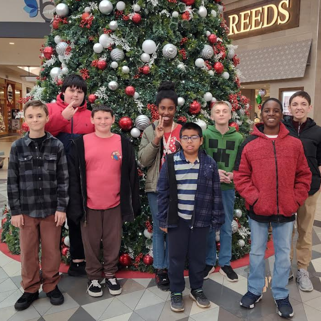 students with teachers in front of christmas tree