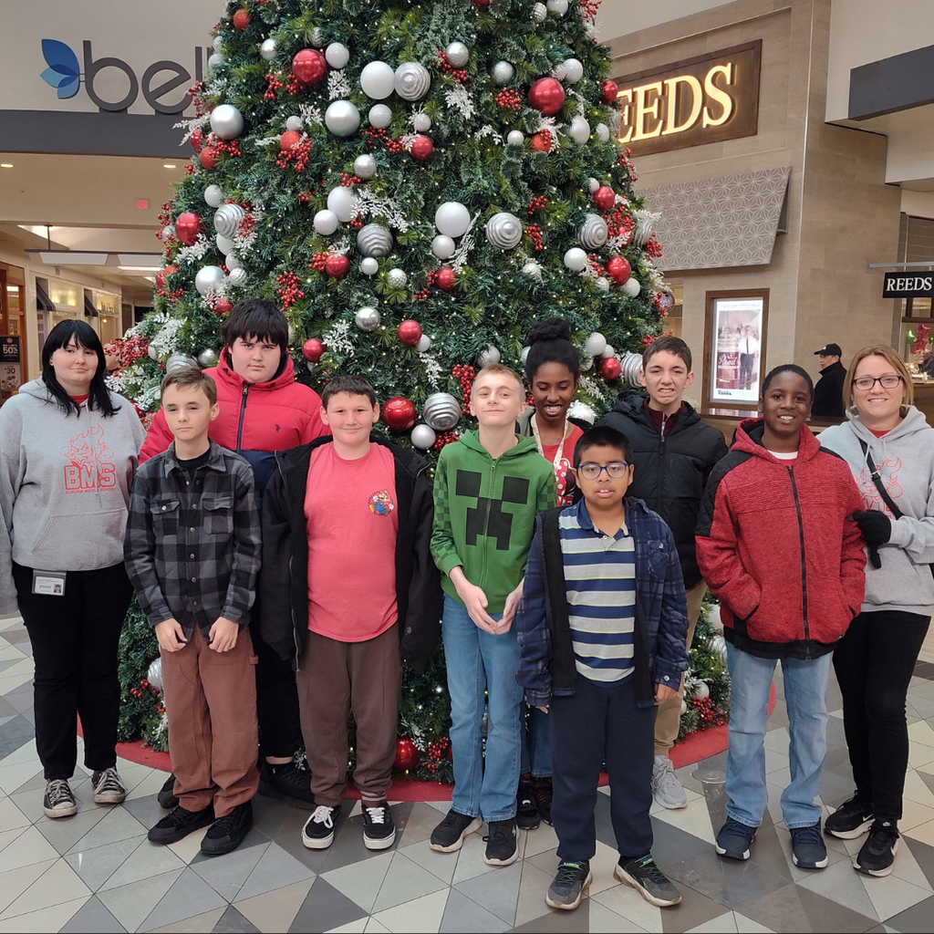 students with teachers in front of christmas tree