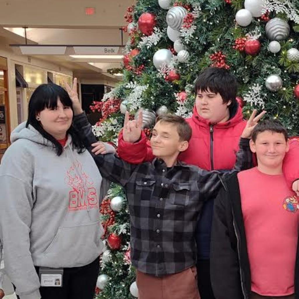 students with teacher in front of christmas tree