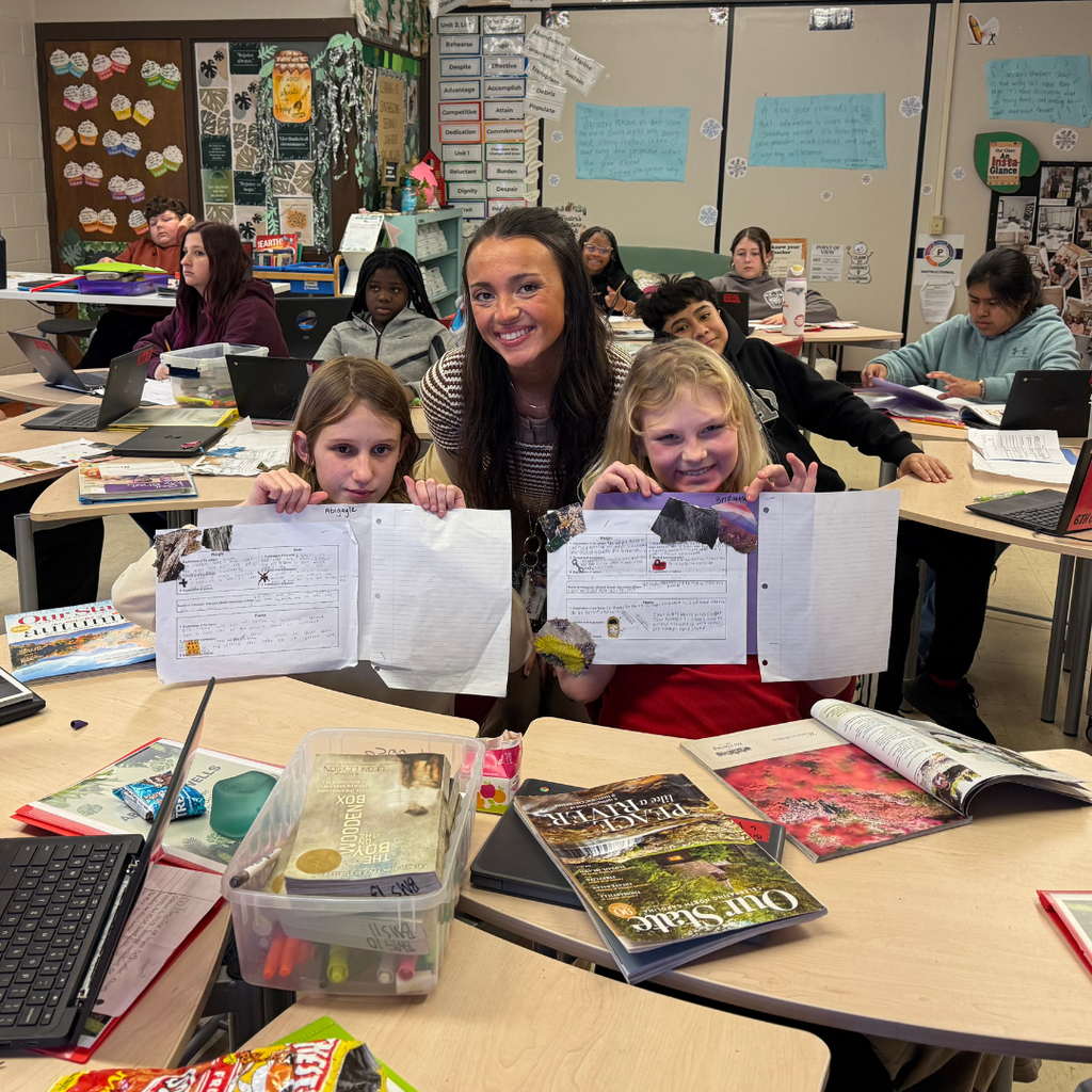 students with teacher at desks holding projects