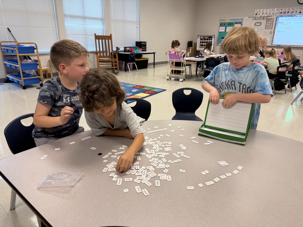 1st graders working on a sentence building activity at a table