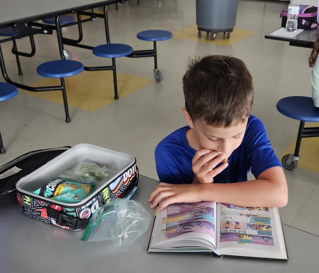 1st grader eating & reading 