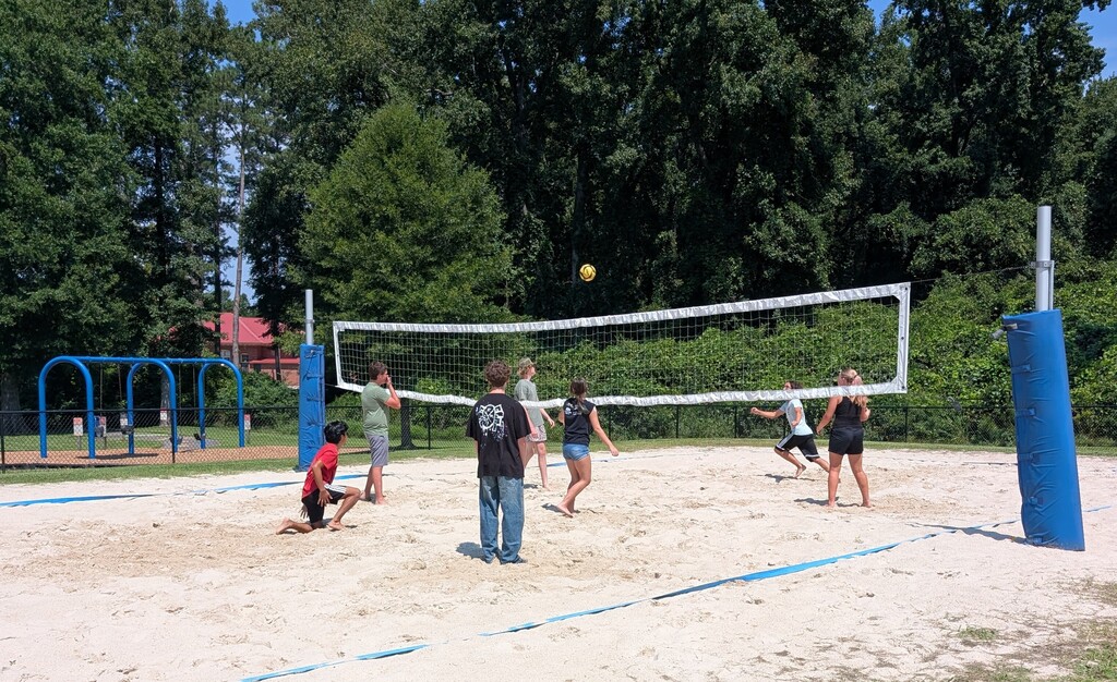 Students run to meet up with the ball during a volleyball match