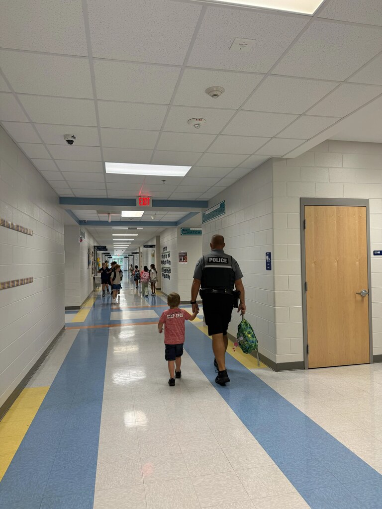 SRO walking down the hallway holding a kids hand