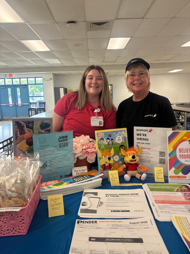 Kitchen staff stands at welcome table for open house to display child nutrition information to parents and incoming students