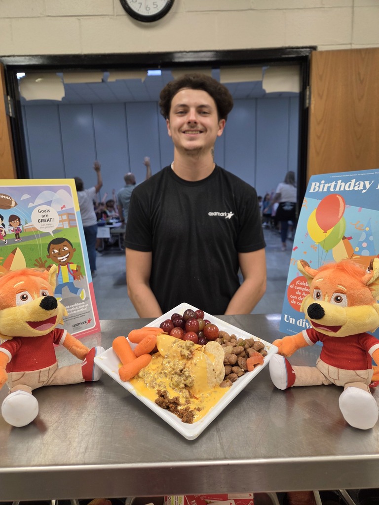 Staff member at Topsail Annandale Elementary stands behind a display plate with Beef Nachos, carrots, grapes, and beans