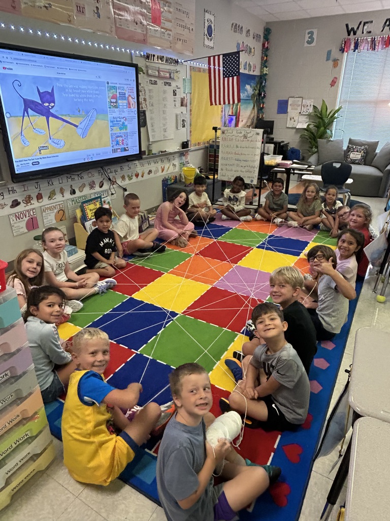 students sitting on a carpet making a class friendship web