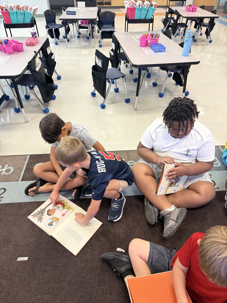 first grade students reading in small groups on the carpet