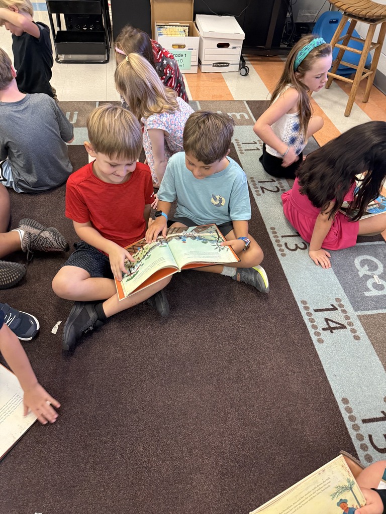 first grade students reading in small groups on the carpet