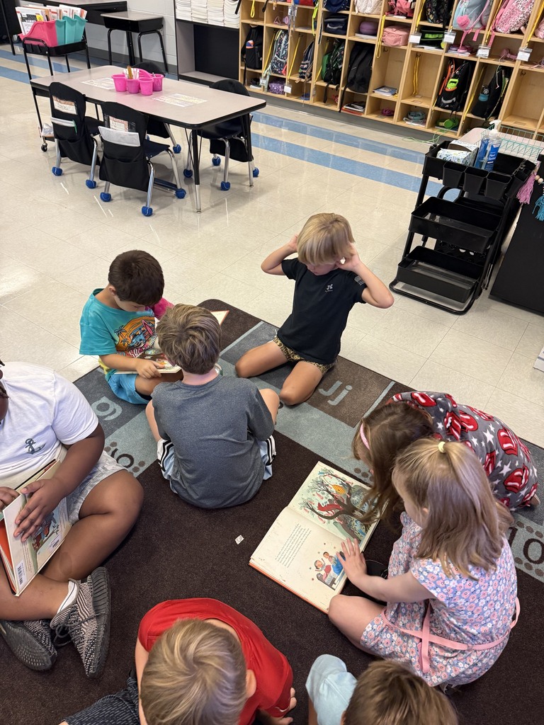 first grade students reading in small groups on the carpet