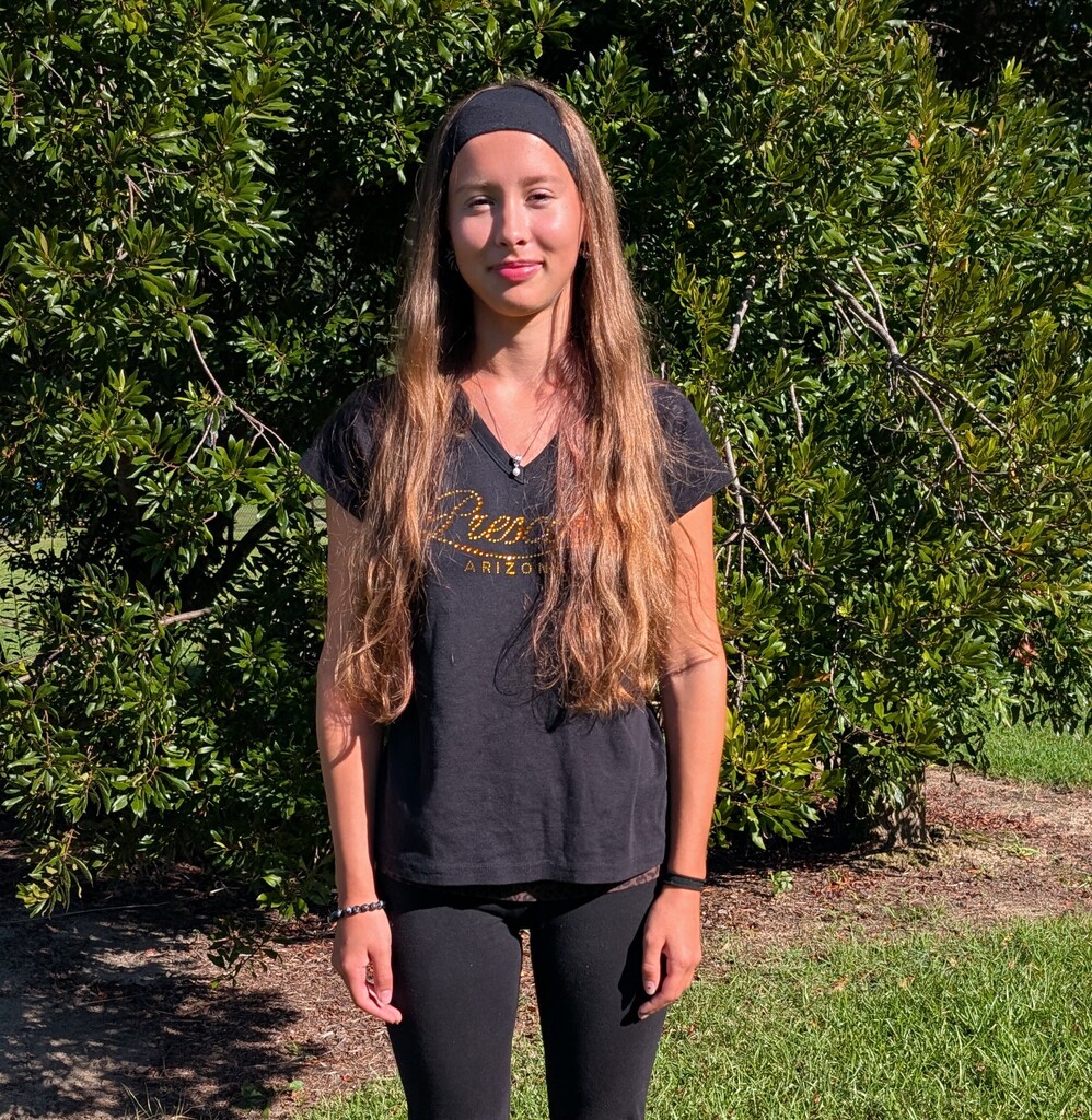 Image of student standing outside in front of bush