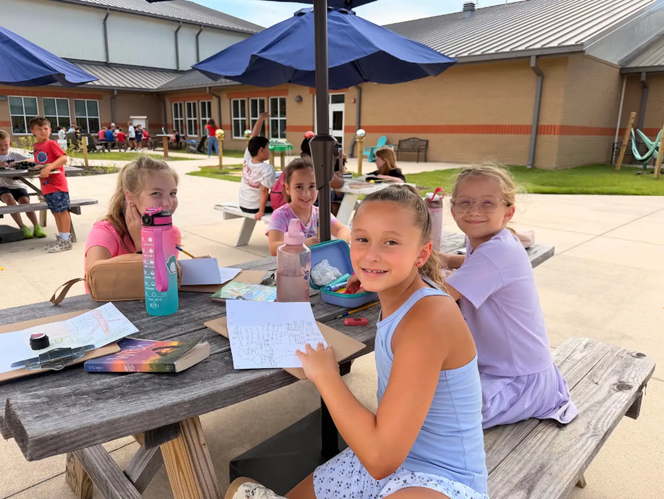 4th graders working outside at a picnic table