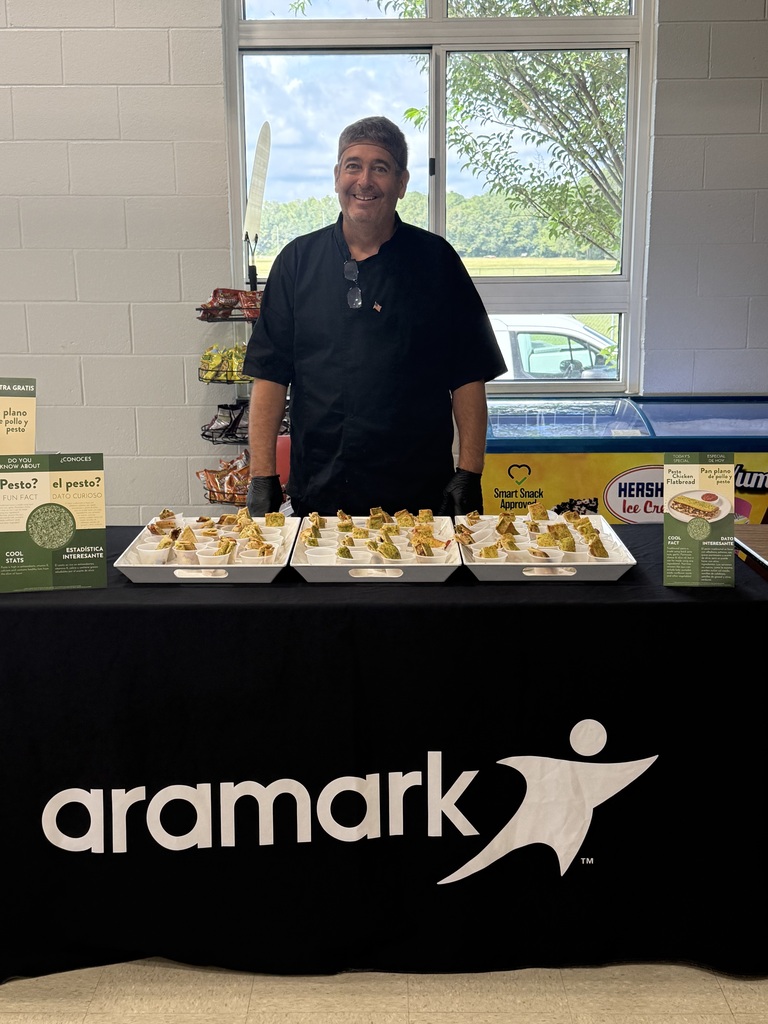 Aramark's Chef Jeff stands behind a table of Pesto Chicken Flatbread samples ready to serve students.