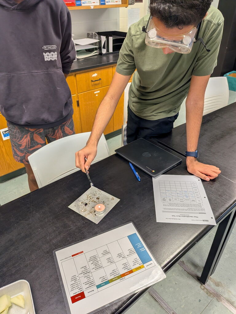 student observes aftermath of burning textile sample