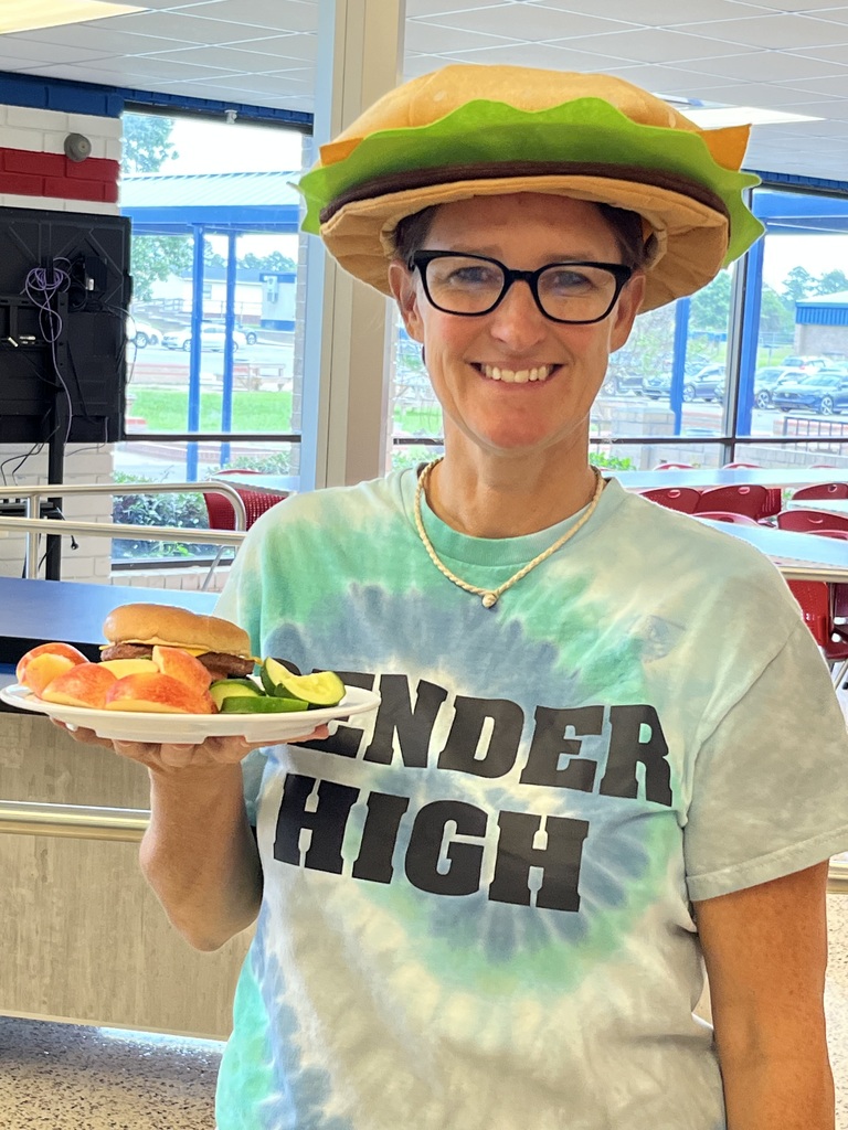 Child Nutrition Manager holds plate of food while wearing a Cheeseburger hat on National Cheeseburger Day!