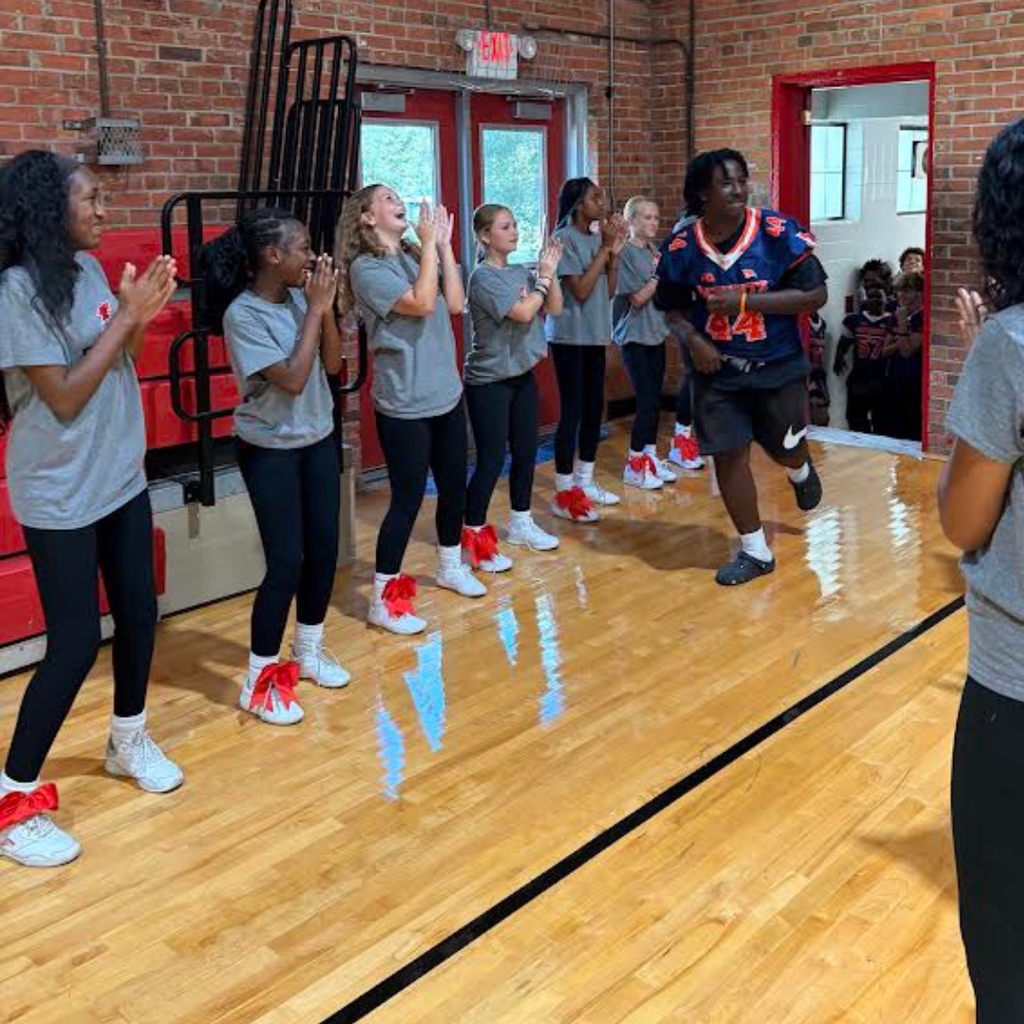 football player at pep rally with cheerleaders