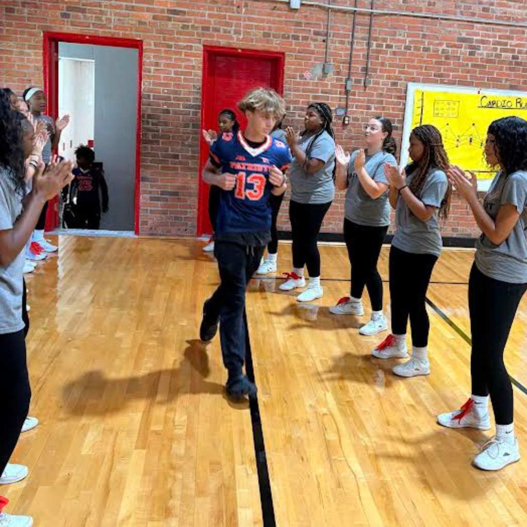 football player at pep rally with cheerleaders