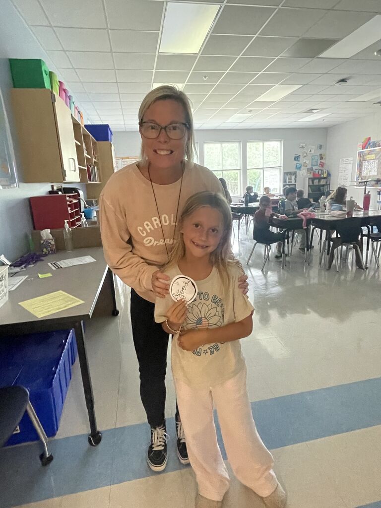student holding a "do good" sticker
