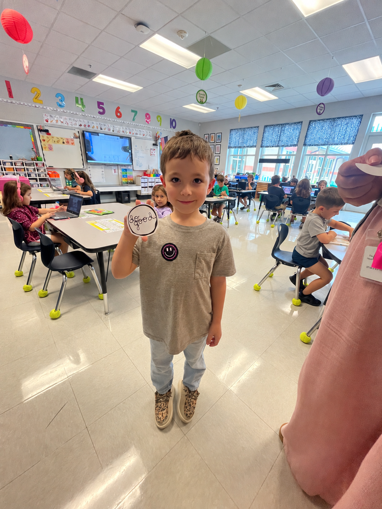 student holding a "do good" sticker