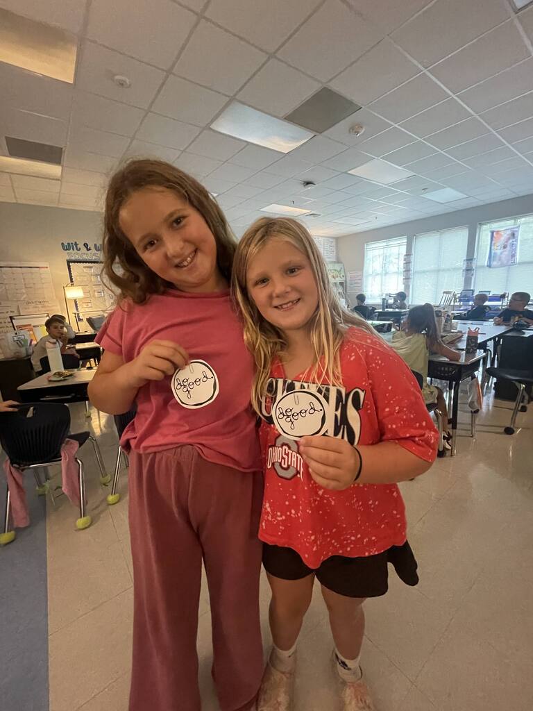 student holding a "do good" sticker